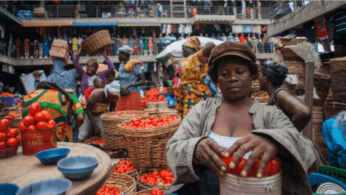 A female pepper seller filling up a bowl of tomato at the market